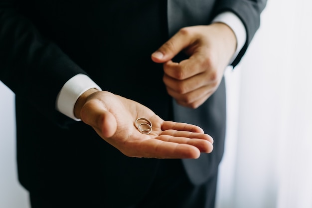 Close up of wedding rings on groom palm