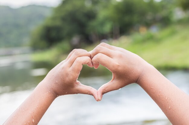 Close up wet hands with heart sign at the river in Thailand