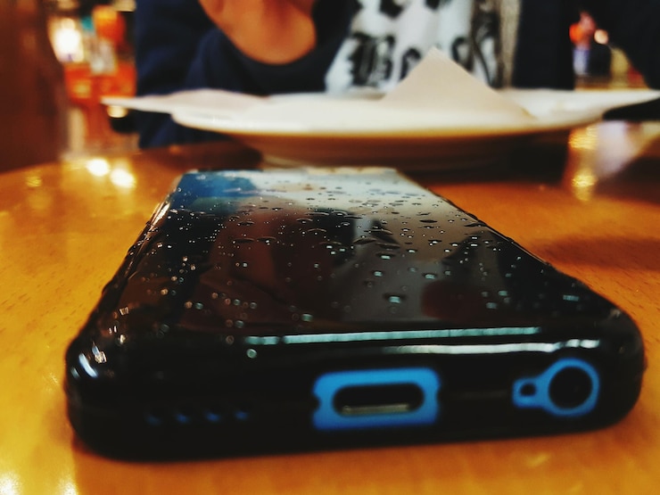 Photo close-up of wet smart phone on table