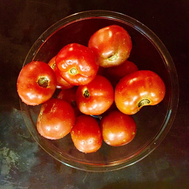 Photo close-up of wet tomatoes in bowl on table