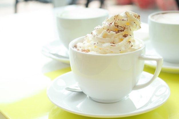 Close up of whipped cream topped with chocolate on hot cocoa drink.