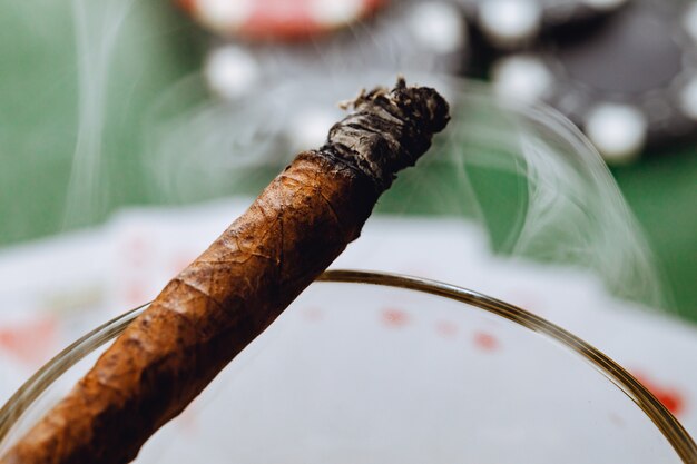 Photo close up of whiskey glass and cigar on green background