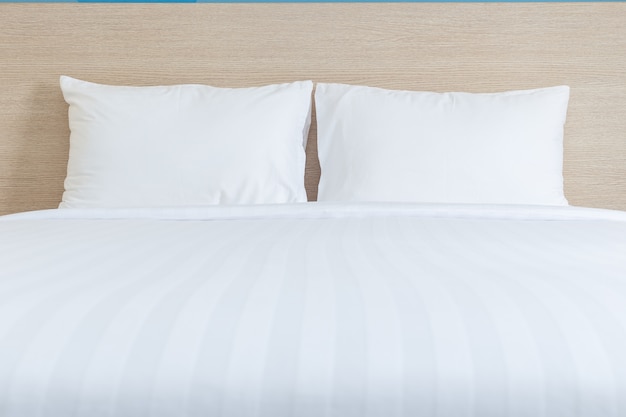 Photo close up white bedding sheets and pillow in hotel room