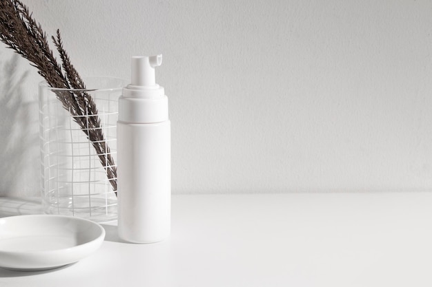 Close-up of white bottle on table against wall
