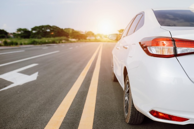 Close up of white car on a scenic road with sunset Car on the road surrounded by natural landscape Concept for travel in holiday