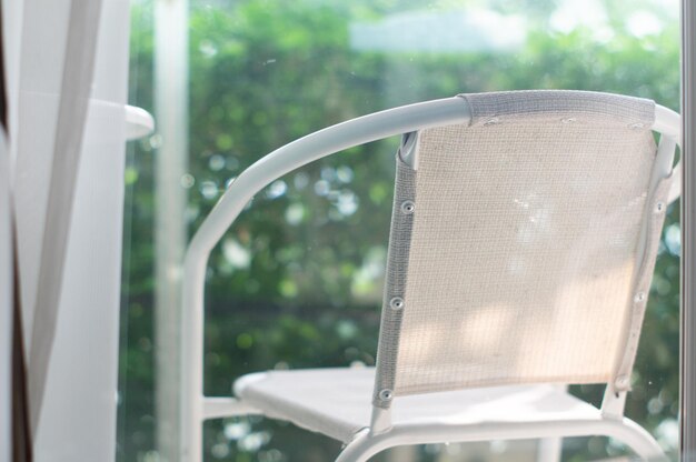 Photo close-up of white chair in garden behind window