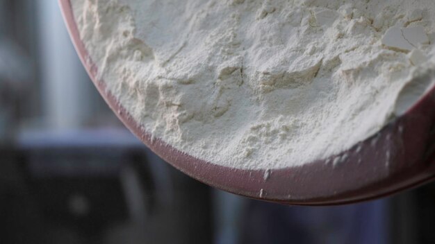 Close up for white flour being put to the iron bowl at the bakery bread products concept stock