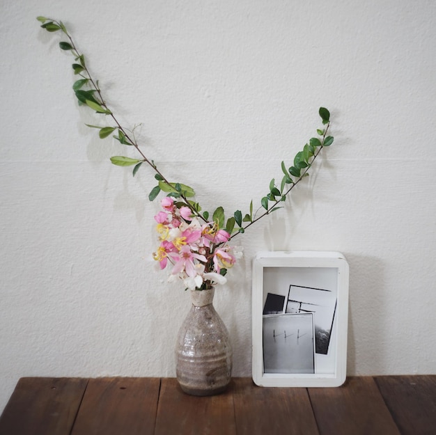 Photo close-up of white flower vase on table against wall at home