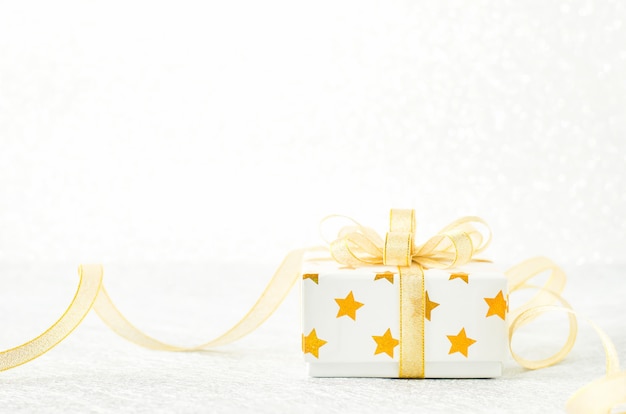 Close up of white gift box with golden star pattern and gold ribbon bow