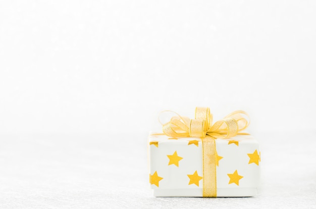 Close up of white gift box with golden star pattern and gold ribbon bow