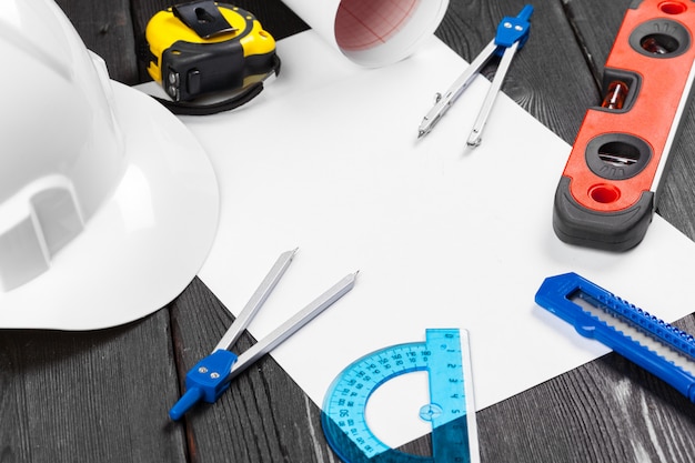 Close up white hardhat and variety of repair tools with copyspace in the middle over wooden 