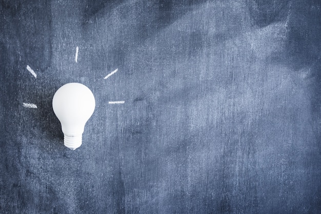 Close-up of white light bulb on blackboard