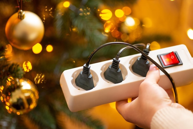 Close up of white multiple electrical socket in woman hands with three plugs in it close up