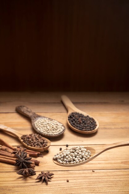 Close up white pepper in wooden spoon surround with spice powder on wooden table