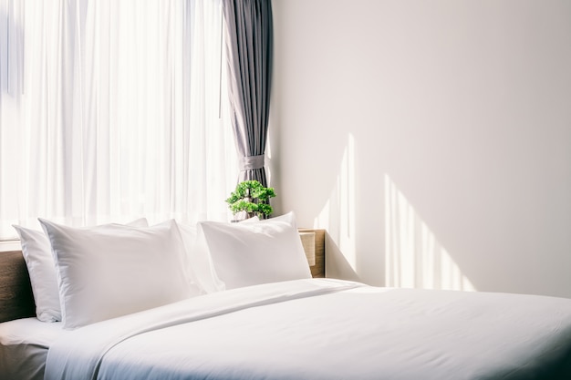 Close-up of white pillow on bed decoration with light lamp and green tree