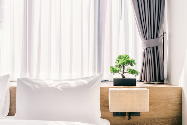 Close-up of white pillow on bed decoration with light lamp and green tree