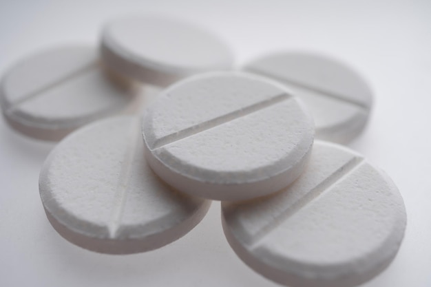 Close up of white pills on white background, medicine and health care concept