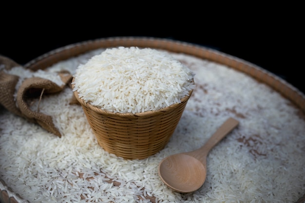 Chiuda in su di riso bianco sul cestino di legno.