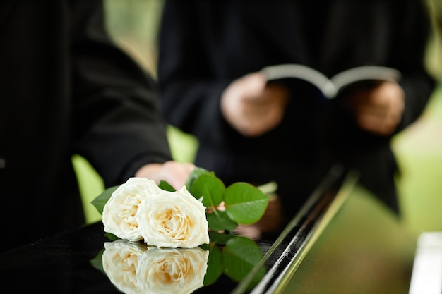 Close up of white roses on coffin at outdoor funeral ceremony copy space