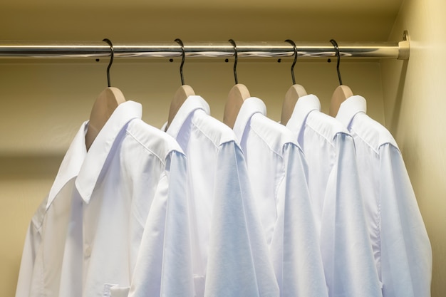 Close up of white shirts hanging on coat hanger in wardrobe