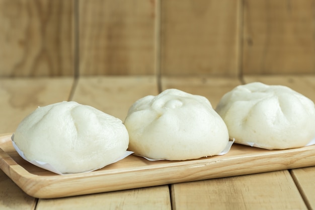 Photo close up white steamed buns on wooden tray