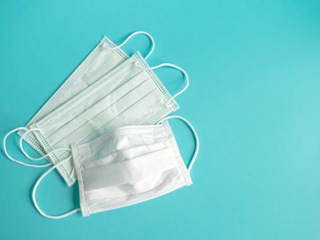 Close up white surgical face mask on blue green background , equipment mask to protect a man health from flu , coronavirus infection , Health care concept