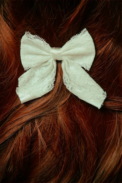 Close up of white tied bow on brown hair