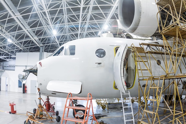 Close-up white transport airplane in the hangar. Aircraft under maintenance