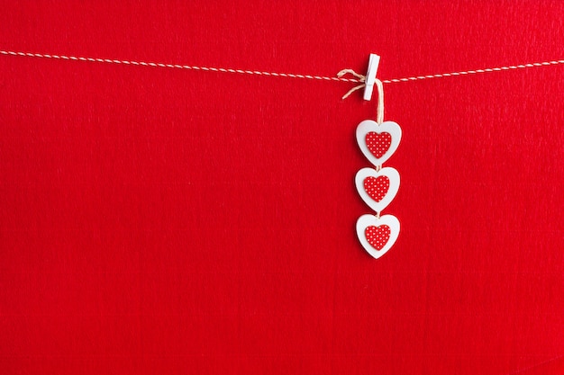 Close up of White wooden heart simbol on red paper background