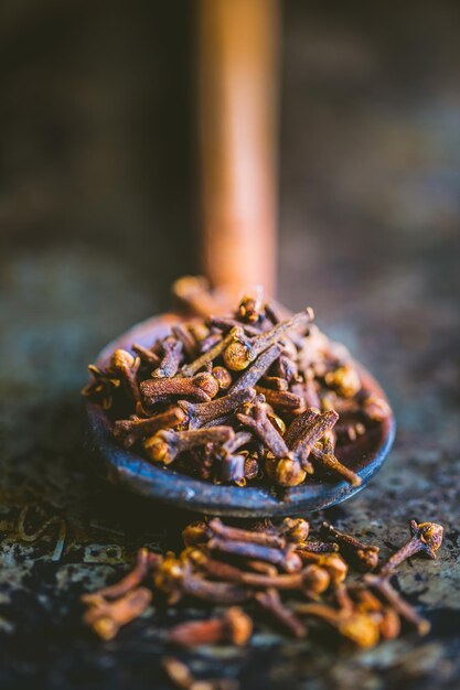 Close-up of whole cloves on a wooden cooking spoon