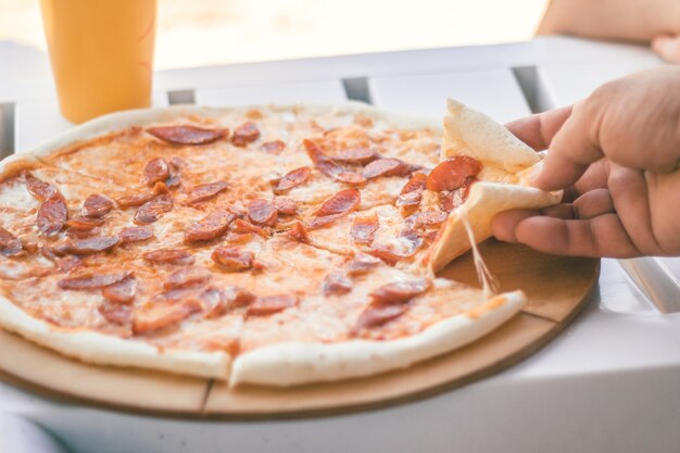 Close-up whole pizza with sausages and cheese. Beach food.