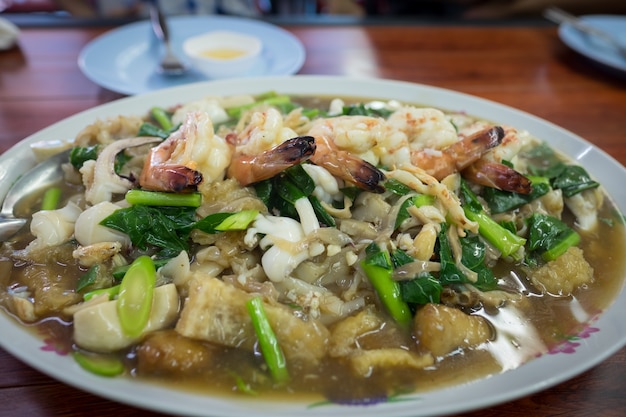 Фото Закройте широкую рисовую лапшу в соусе. морепродукты широкая рисовая лапша в соусе смешивает овощи.