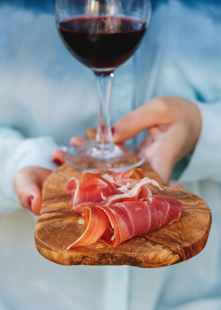 Photo close-up of wine glass and prosciutto on wooden serving board