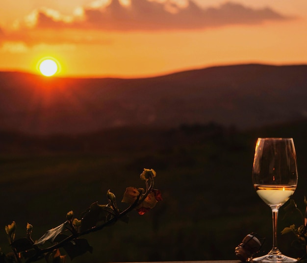 Близкий план винного стакана на фоне неба во время захода солнца