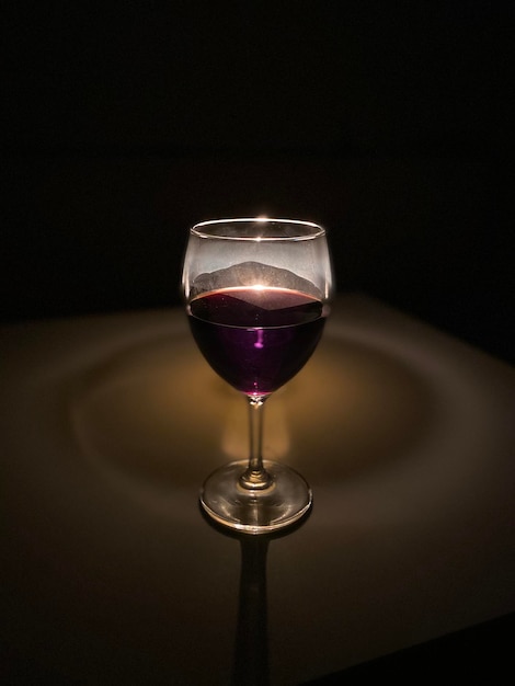 Foto close-up di un bicchiere di vino su tavola su sfondo nero