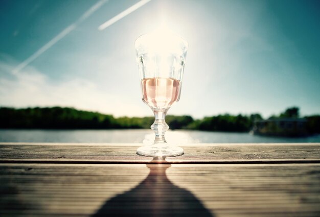 Foto close-up di un bicchiere di vino sul tavolo contro il lago