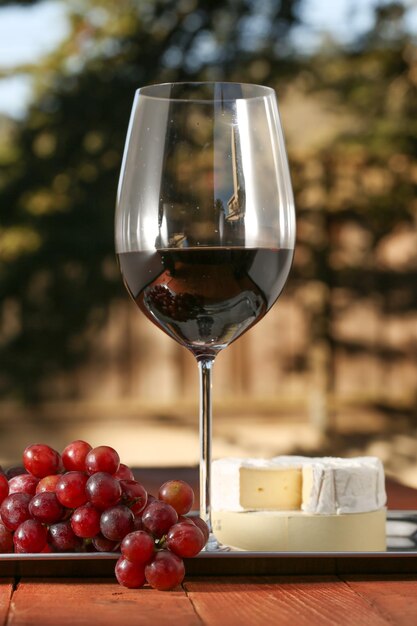 Foto close-up di un bicchiere di vino con uva e formaggio su tavola