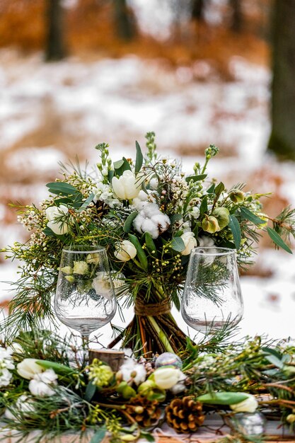 Photo close-up of wineglasses by flower arrangement on table