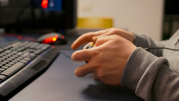 Close-up of wireless joystick during online championship in gaming hone studio. Competitive player man playing video game tournament with new graphics using professional RGB equipment