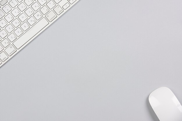 Photo close-up of wireless keyboard and mouse on the corner of gray background