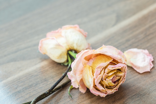 Photo close-up of withered pink roses on wooden table