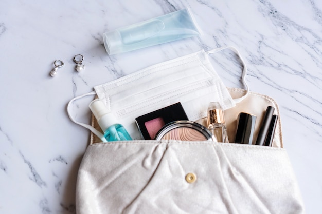 Close up of woman accessories, sanitizer, alcohol spray and protective face mask on pouch, Beauty concept. Must have item in 2020 concept. Flat lay