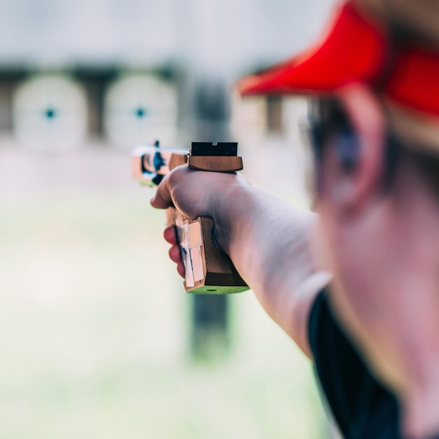 Foto close-up di una donna che mira una pistola all'aperto