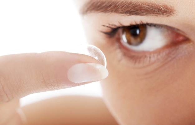 Foto close-up di una donna che applica le lenti a contatto su uno sfondo bianco