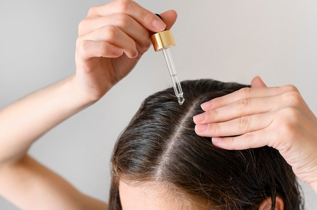 Foto donna del primo piano che applica siero per capelli