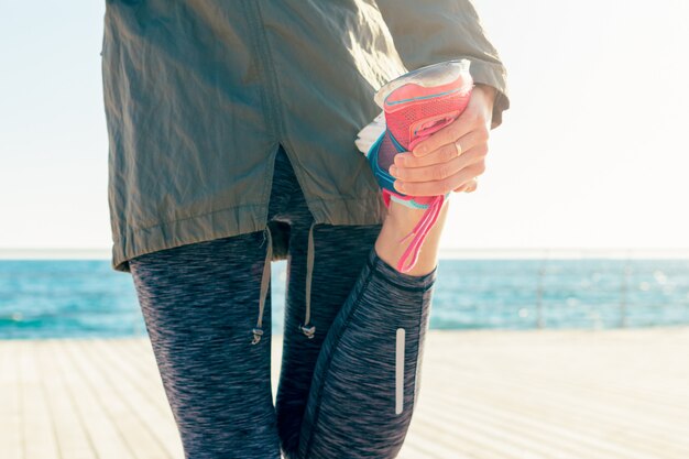 Крупный план женщины на пляже растягивает мышцы на ноге