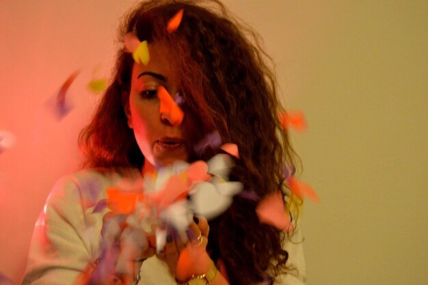 Photo close-up of woman blowing petals against colored background