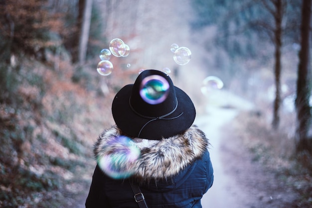 Foto close-up di una donna che soffia bolle di sapone sulla neve