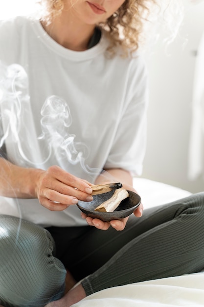 Foto primo piano della donna che brucia salvia a casa per il relax