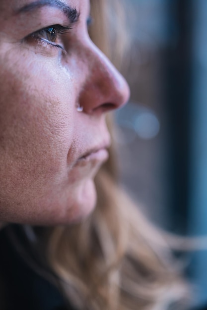 Close-up of a woman crying.a tear runs down her face.concept of\
depression, sadness and nostalgia.